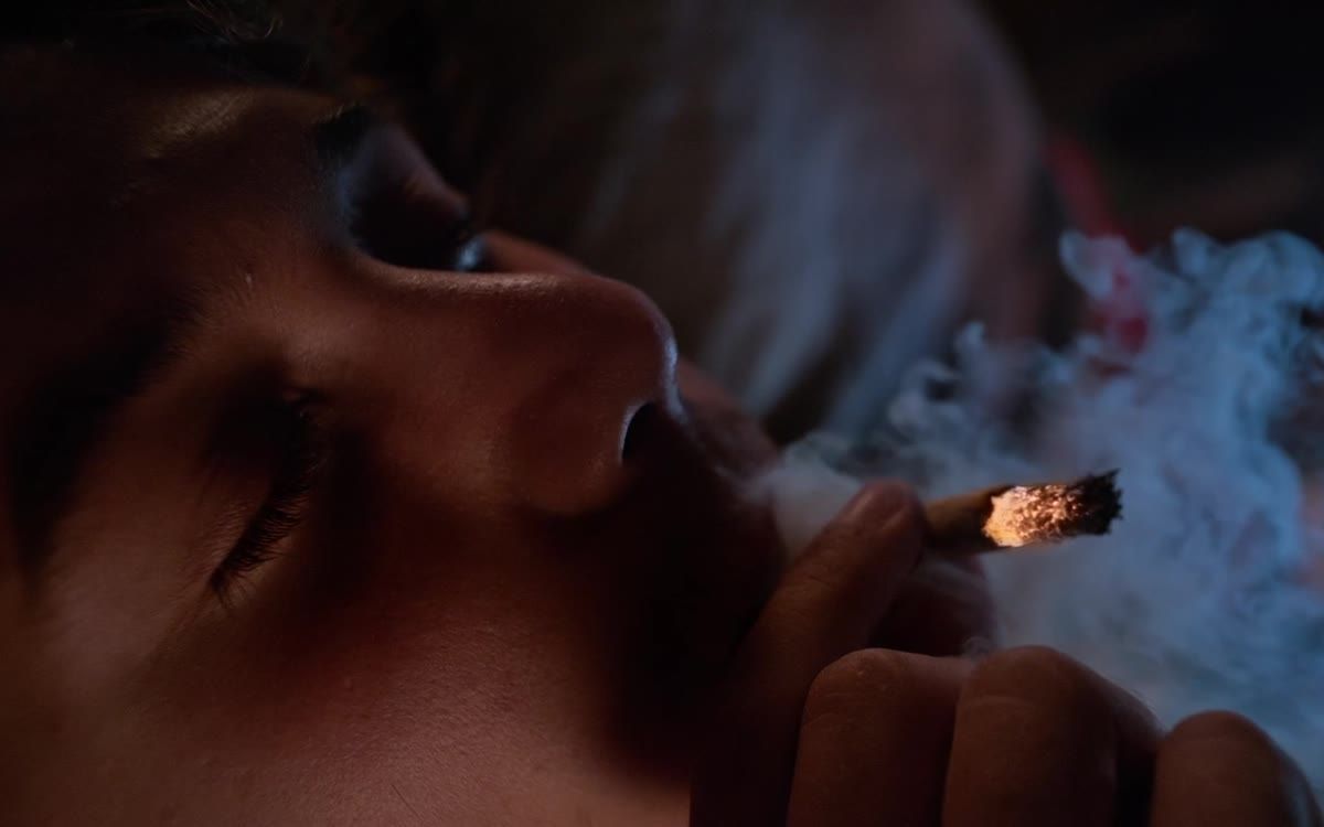Un chico fuma en la penumbra