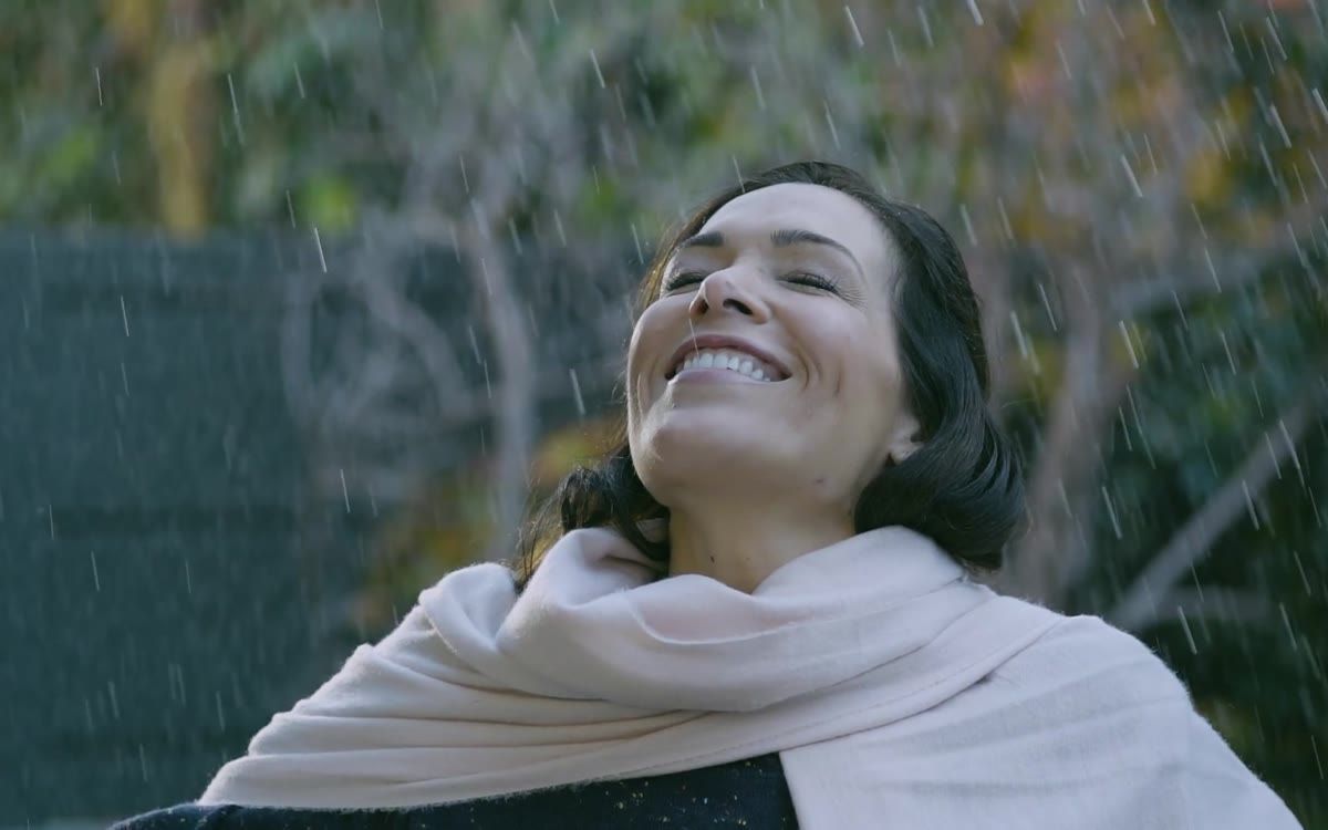Una mujer sonríe bajo la lluvia