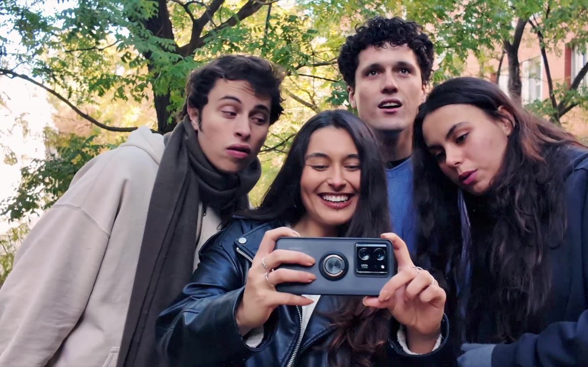 Cuatro jóvenes miran la pantalla de un móvil